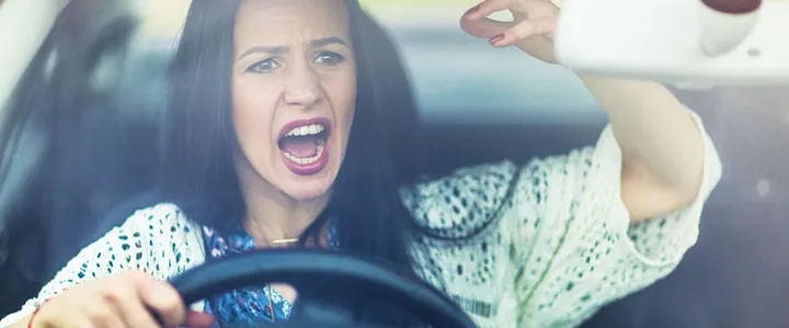 An angry woman shouting while gripping the steering wheel